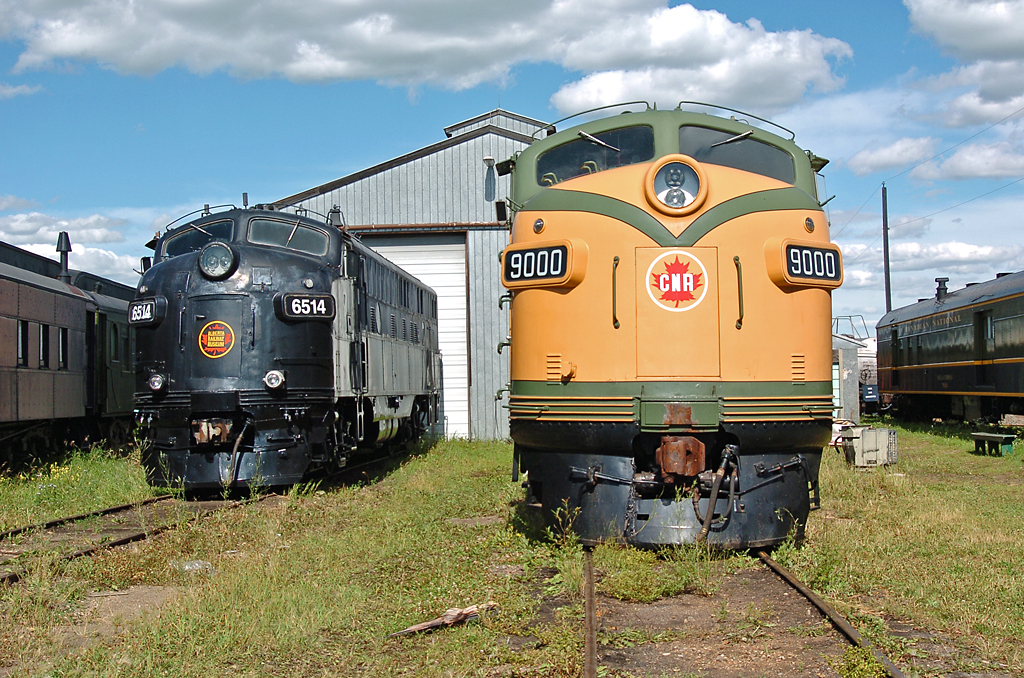Two F-units, Ex-CN F3A 9000 and ex-AC FP9 6514, sit in front of the Alberta Railway Museum's "Calder" shop.