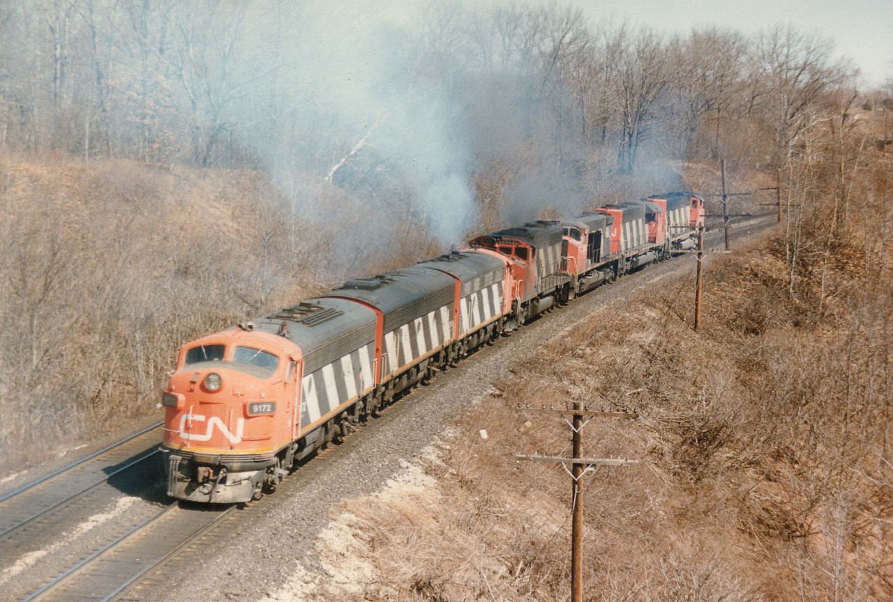 At a location which I refer to in my old notes as Bayview East, (now 'Snake') the power for CN #392 smokes it up en route to its transfer down to Burlington West where it parked in behind the station in the former industrial yard awaiting further assignment.  The photo is shot from Plains Rd West bridge at a location close to where old Hwy 6 and Hwy 2 used to come togther under the junction name of Wolfe Island, which can be seen engraved in the new replacement concrete structure at the entrance to the railfans' Walk Bridge.  Poweer swirling under clouds of white exhaust are: CN 9172, 9195, 9175, 2513, 5190 and 9518. My assumption is the last four units ran light into Hamilton to pick up the A-B-A and the consist of #392 is tucked away at Aldershot yard. Or was this a Fort Erie to Toronto train? Anyone??