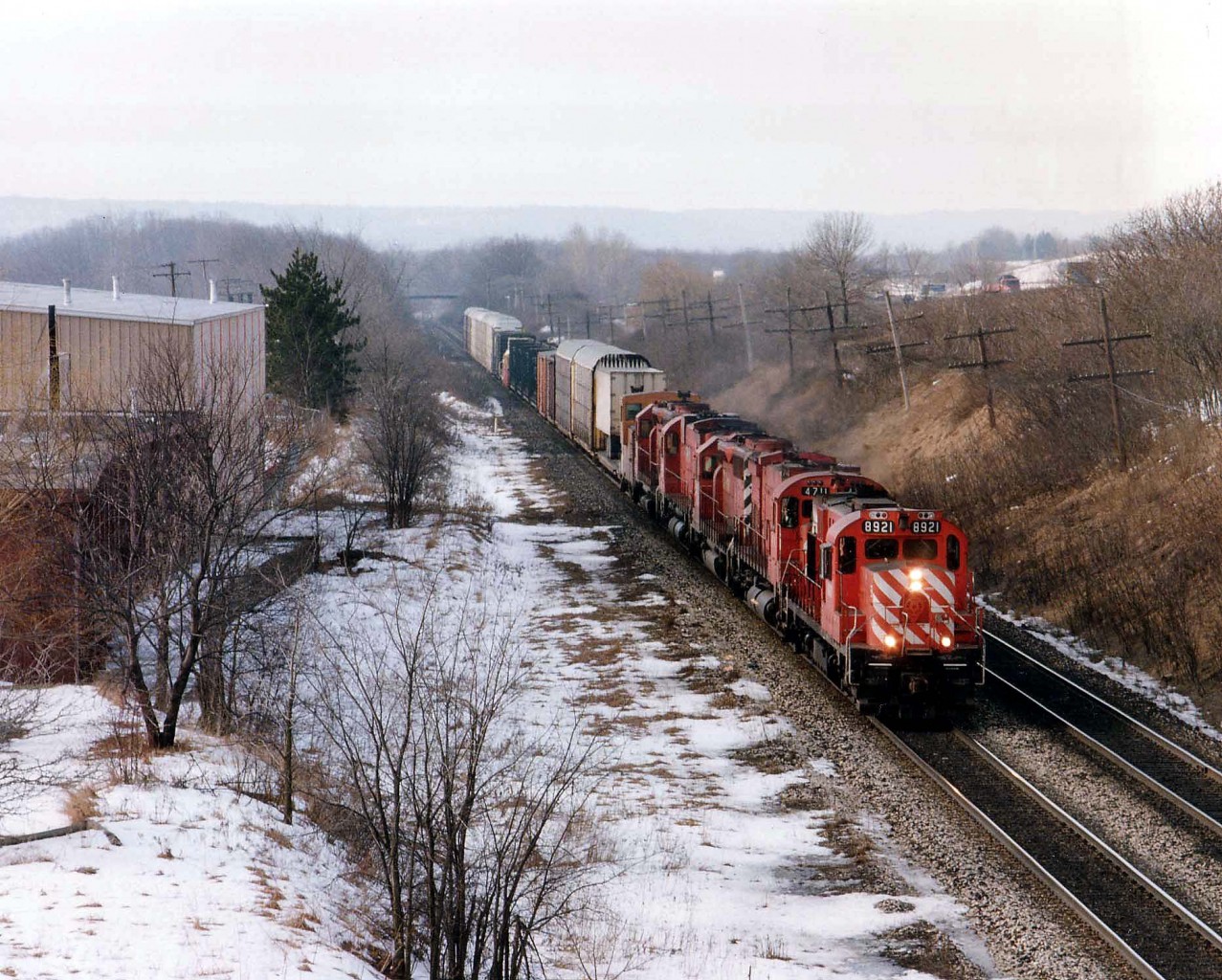 A very overpowered and short CP #557 on February 5, 1993 was eagerly awaited by the local railfan population. No wonder!!  It featured one-of-a-kind CP 8921 (RSD-17)followed by 4711 (M-636 converted to caterpillar engine in 1988)SD40-2 5601 (ret'd 2002), CP 4743 (another Big M) and SD40 5547 (ret'd by 2004) and maybe a dozen cars in tow. This image was taken on a rather warm morning for dead of winter, ground fog obvious from the Lemonville Rd bridge over the CN in Aldershot,ON.