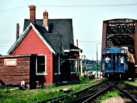 Like a scene from long-ago branchline railroading, Conrail crew watches and waves from the Van as the CR transfer heads back Stateside on a late afternoon in June of 1979. Note the US-bound merchandise is in crates. The vans are history, as is the old Bridgeburg B-1 Station. The building was jacked up and moved across the tracks to be trucked to the RR theme park on Central Av to keep CN 6218 and Ridgeway Sta company. Why it was then painted a sickly yellow I don't know. Bridgeburg was the original community name. Fort Erie was further to the south. Now, of course, they are one.