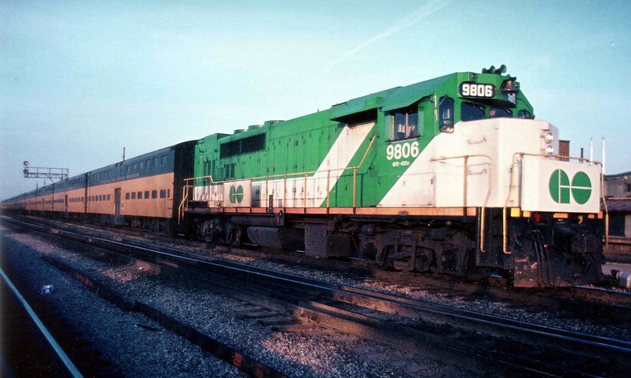 Seeing that ridership was continually growing, it became time for GO Transit to look into double-decker coaches for their busier lines. Chicago NorthWestern, which runs a commuter service in Chicago, was able to loan GO a number of coaches in order they be tried out to rate their performance. It was early in the year when they were on trial here, which, because GO runs early morning and late afternoon, made it very difficult to get enough light in order to catch these in action.  This is a late day view at Burl. West, GO 9806 the power westward, with a considerable number of CNW bilevels in tow. The date on my slide is illegible, but according to Trackside Guide, this GP40TC was new in 1966 as #606, became renumbered 9806 in 1970 and then reverted to 506 in 1975, so this must be April of 1975 if the book is correct.  Incidentally, most fans know the former station here as "Burlington West", but it was previously the station known as "Freeman" which was the name of the community here before it was swallowed up by Burlington expansion in the 1960s.