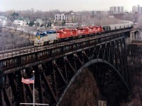 History in the making as the First Seamless International Grain Train makes its way across the steel arch bridge connecting Niagara Falls Ontario with its American counterpart. The D&H 7309 was ushered over to CP Montrose Yard for the brief ceremony as the SOO had brought the train to Canada and the CP unit added on to represent the run thru Ontario. As the D&H led the train to New York State and on to Albany, standing in this pitiful morning drizzle for a couple of hours was a real downer. Also the fact that N.F. city police had to investigate my illegal location on Robert Moses Parkway, they had to call the State Police who in turned called Border Patrol and it was another couple of hours explaining I was NOT involved in any criminal activity but instead wanting to capture this "train event" on film. I must admit the police were shaking their heads going thru my notebook. "All these pictures"??? One of them asked..........  As usual, in the end it was all worth it; even the fact I was over an hour late for work.  Power is D&H 7309, CP 5529, SOO 6612, 6601 and 780. The large building in upper center of photo is the old Kind Eddy Hotel, also now a part of history.