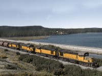 4 Wabush Lake Railway RS18's with a loaded ore train heads east on the QNSL-Wabush joint Northernland Subdivision. The Wabush will deliver the ore to Emeril Junction where QNSL power and crews will continue onto the Port at Sept Iles QC.