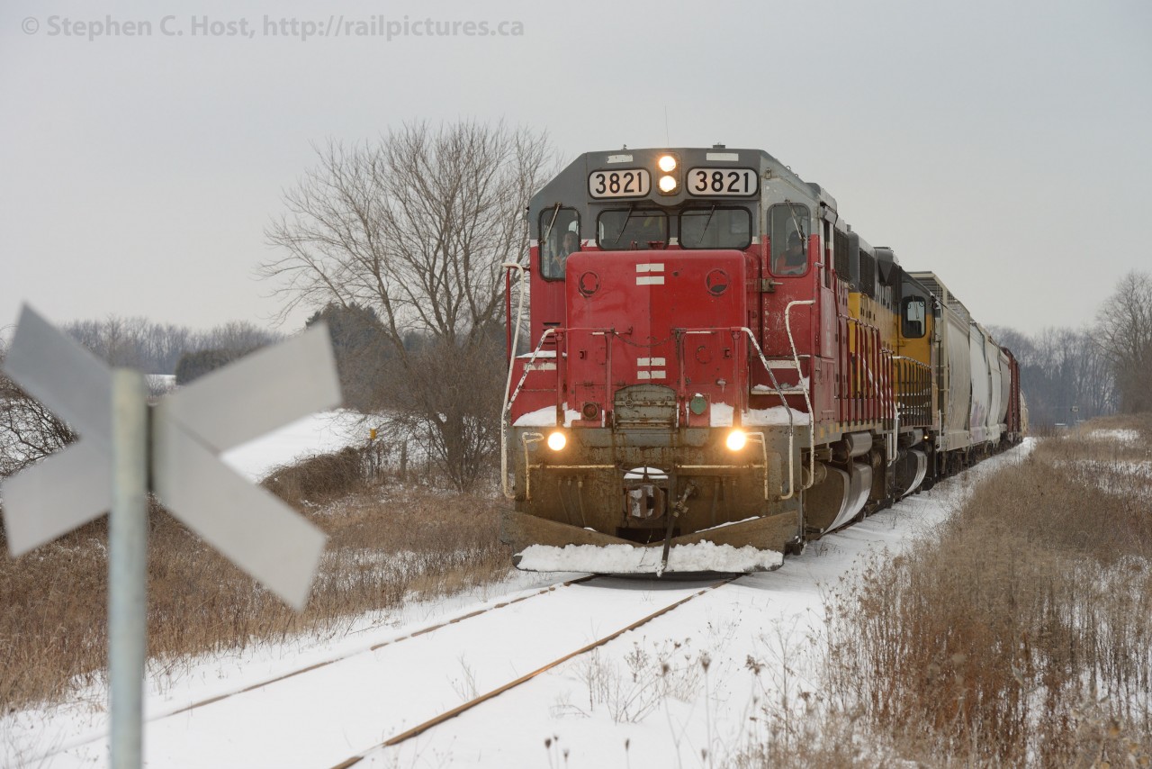 2013 arrives  and the Goderich-Exeter 580 trundles southward on the former Fergus subdivision on a cold winters day. Cold winter Branchline railroading with two engines and eight cars. At this private crossing, the owners have erected metal crossbucks, a combination of the old "Rail Road / Crossing" 45 degree angle variety with the Canadian (and European) red and white reflective tape for a face. Did I mention it was very cold? Brrrrrrrrrrrrrrr.