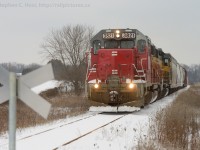 <b> 2013 arrives </b> and the Goderich-Exeter 580 trundles southward on the former Fergus subdivision on a cold winters day. Cold winter Branchline railroading with two engines and eight cars. At this private crossing, the owners have erected metal crossbucks, a combination of the old "Rail Road / Crossing" 45 degree angle variety with the Canadian (and European) red and white reflective tape for a face. Did I mention it was very cold? Brrrrrrrrrrrrrrr.
