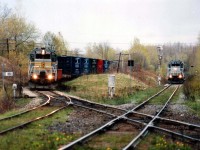 Two trains meet at the Lennoxville diamond. Quebec Southern Rwy 504 and 500,at Sherbrooke Sub., wait for thru freight BAR 350, AMTK 387 and HATX 176, a Canadian-American Rwy (CDAC) train on QSR trackage, mile 66. It will cross the diamond eastward and will then be travelling on CDAC rails. The QSR local is on CN Sherbrooke Sub. trackage. The in and out sun, a fixed lens and the general lay of the land made this a difficult place to shoot.At this time CDAC was part of the Bangor & Aroostook system (BAR).