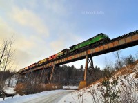 The setting sun catches the side of a Montreal Maine & Atlantic oil train as it rumbles across the trestle at Eastman on a cold February afternoon