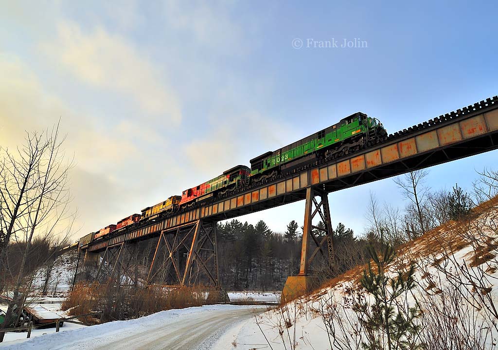The setting sun catches the side of a Montreal Maine & Atlantic oil train as it rumbles across the trestle at Eastman on a cold February afternoon