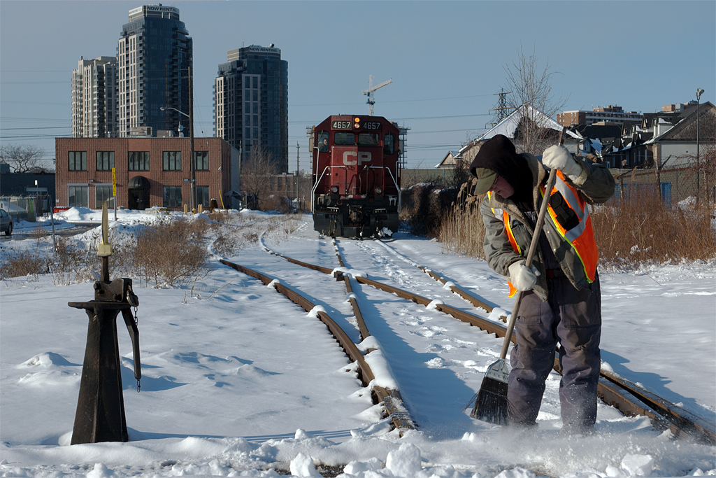 Last night's snowfall adds a little extra elbow grease to the working day of this CP yardman, as his train makes a delivery in Area H.