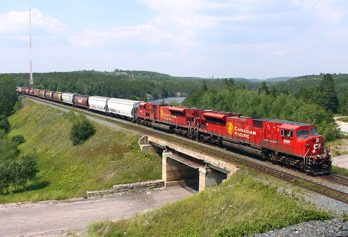 A pair of SD90MACs lead grain loads across the old Hwy 17 underpass at Hawk Lake.