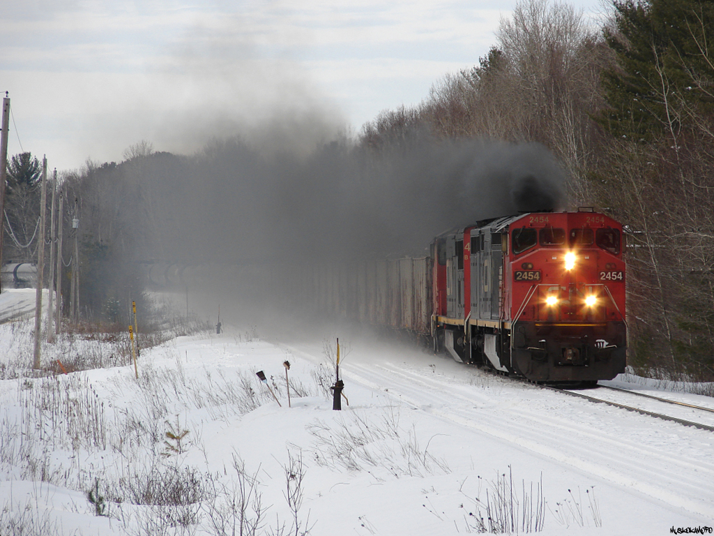 CN M31641 08 - CN 2454 South hacks and coughs her way through Sparrow Lake heading to Smail to meet train 103. Through all that smoke is a train of frozen ballast loads from Milnet, loaded tanks for Nanticoke, some mixed freight and a big cut of empty multis for Southern Ontario.