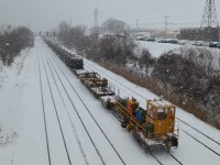 On a mild but very snowy day, the tail end of a rail train (W905) powered by GTW 5933 & GTW 5931 is about to enter CN Taschereau Yard after dropping off some rail on the busy Montreal Sub.