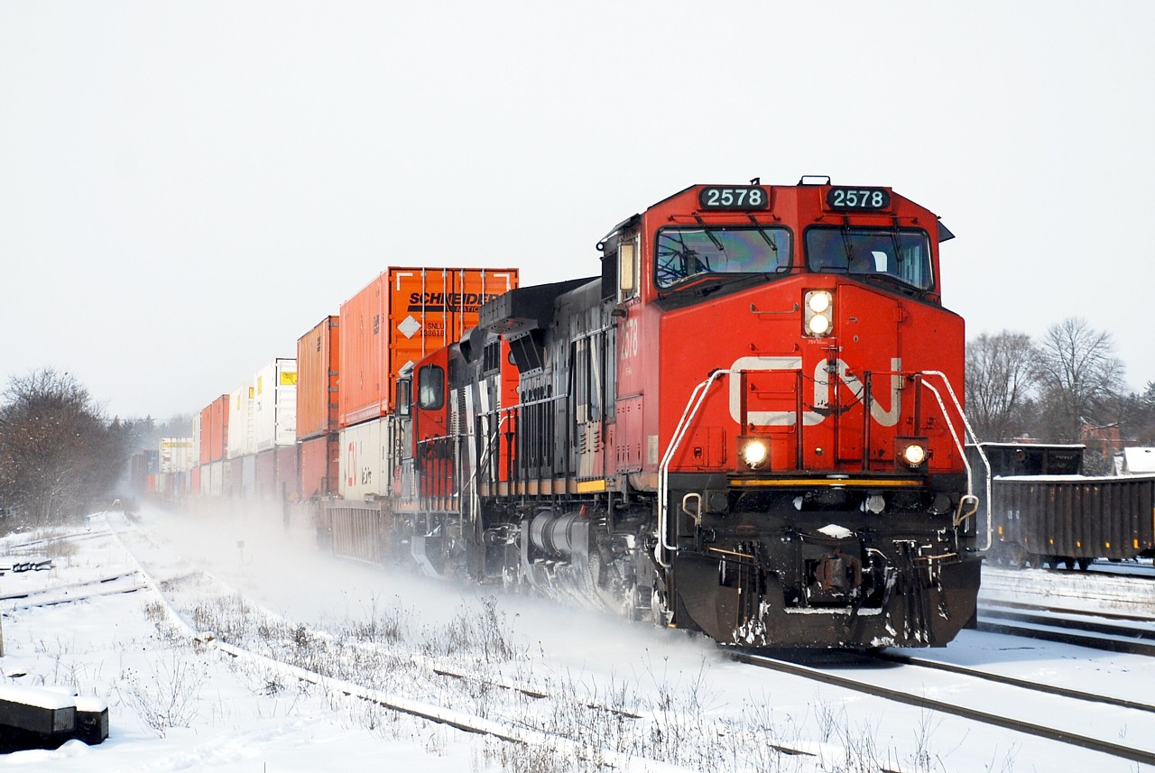 A GP9 in intermodal service! CN 148 kicks up the fresh snow as it rolls through Brantford with CN 4130 trailing. The geep was repaired at Woodcrest Shop and was being transferred back to Mac Yard.
