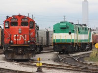 A pair of former GO F59PH sit along side a CN GP9RM while awaiting shipping out to their new owner