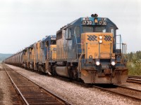 The Dofasco Ore train is pictured rolling by the old wooden Englehart ONR station and offices onto the Temagami Sub en route to the Dominion Foundaries & Steel Ltd. plant in Hamilton. The iron ore pellets being shipped are from the nearby Adams Mine, which is located about 7 miles south of Kirkland Lake, or 15 mi north of Englehart. Power this August 9, 1984 is ONR 1730, 1801, 1804 and 1736, which will give way to CN power at North Bay. Ore was shipped from Adams Mine during the period 1963 until it closed in early 1990, and from the Sherman Mine near Temagami from 1967 until its closure in 1989. As the mines were worked out, it became increasingly expensive to mine the ore and as a result there were no more Ore trains out of north after 1990.