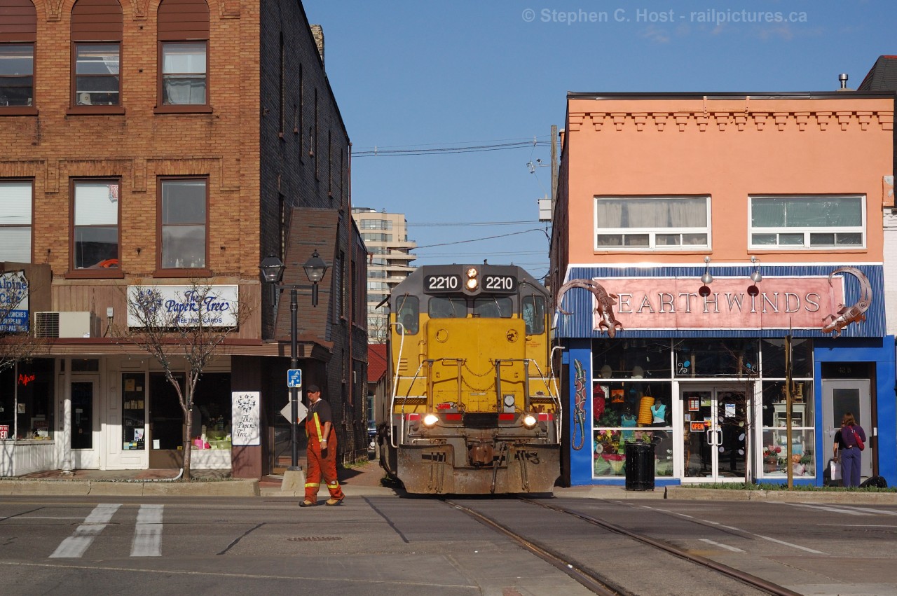 In brilliant glaring evening sun - The conductor for GEXR 582 is flagging King St. as the train emerges from between buildings on the Waterloo Spur - en-route to Elmira.