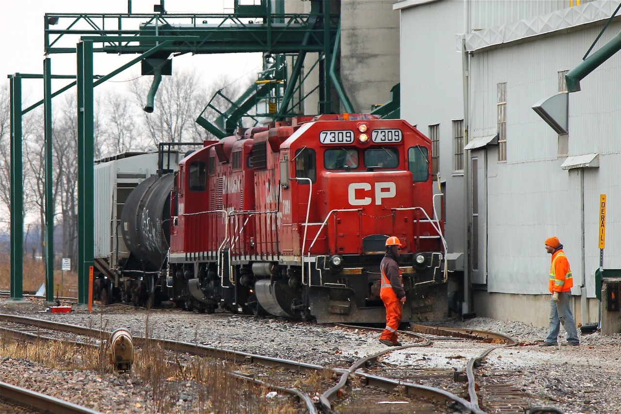 DERAILMENT! Here we see CP Chatham Local T76 on the ground in Kent Bridge at the Thompson's Co-Op facility. As 7309 and 8200 serviced the grain elevator the rails slipped out from beneath 7309's front truck and rolled the North (far side) rail causing a violent rocking with the locomotive slamming up against the side of the building before righting itself. Crews spent several hours assessing the situation and the locomotive remained like this for several days I've been told. 8200 later ran light back to Windsor without 7309.
