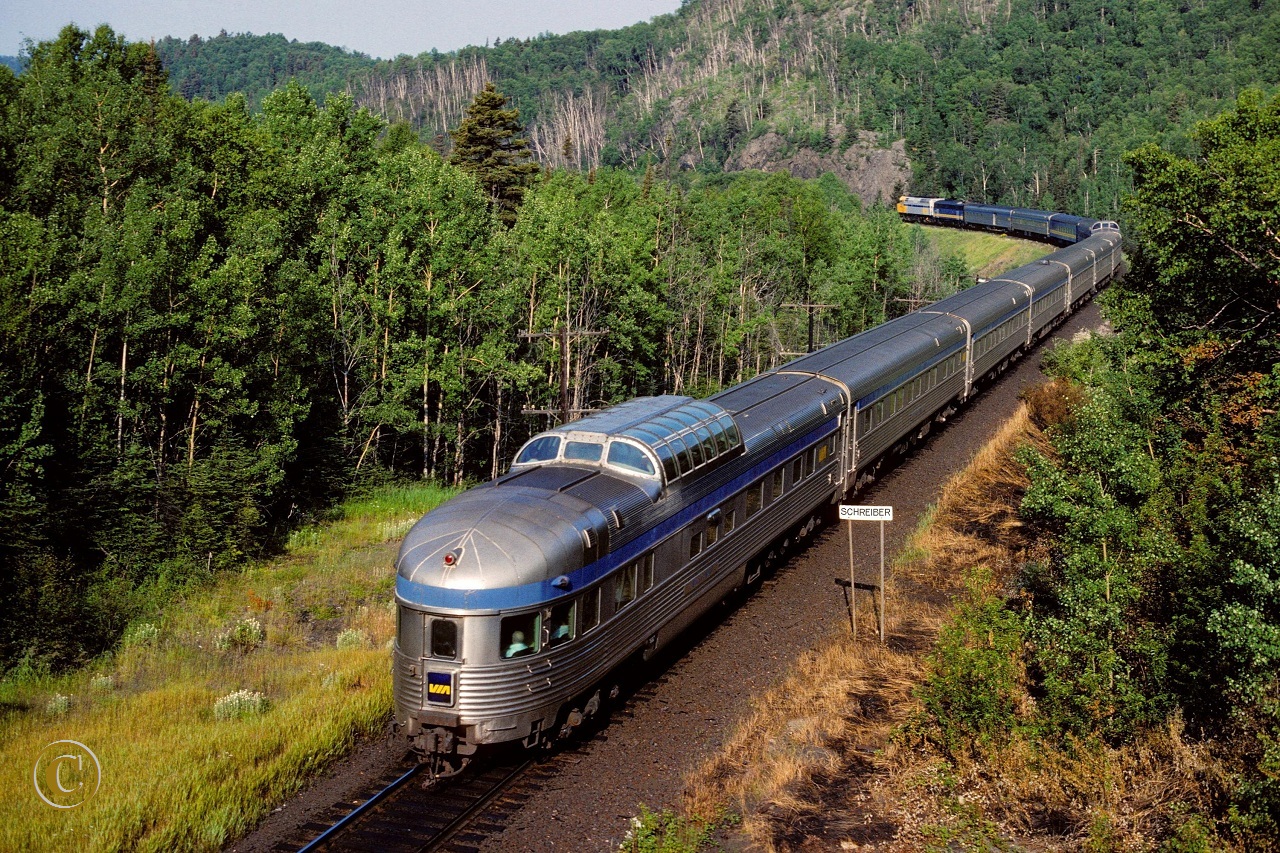 VIA 6424 with train 1, The Canadian, passes the Schreiber mile board at mile 117 on the CP's Heron Bay Sub July 24, 1989.