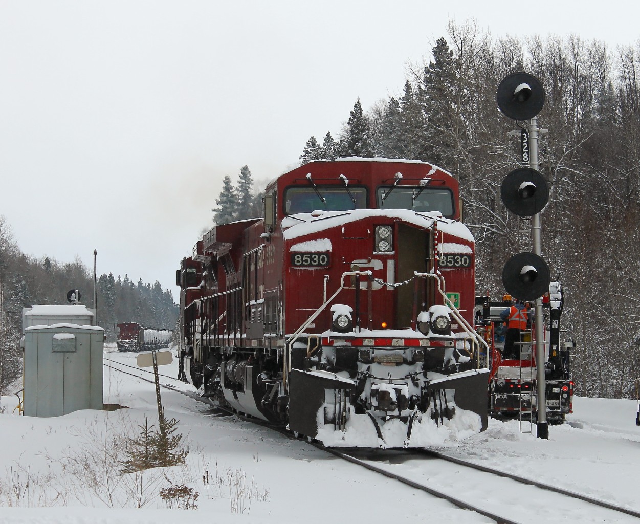 The originating crew on train 608 [crude oil loads] have parked their train in the siding at Gravel during the night.  As the only road access here is near the west switch, the head end power  – cp9702 / cp8530 – was brought  to the west end and positioned in the siding near the tail end remote. The new crew has arrived and is backing the head end power out of the siding onto the main line. They will then proceed eastward  to the east switch, back onto the train and continue on to the next crew change point at Schreiber.