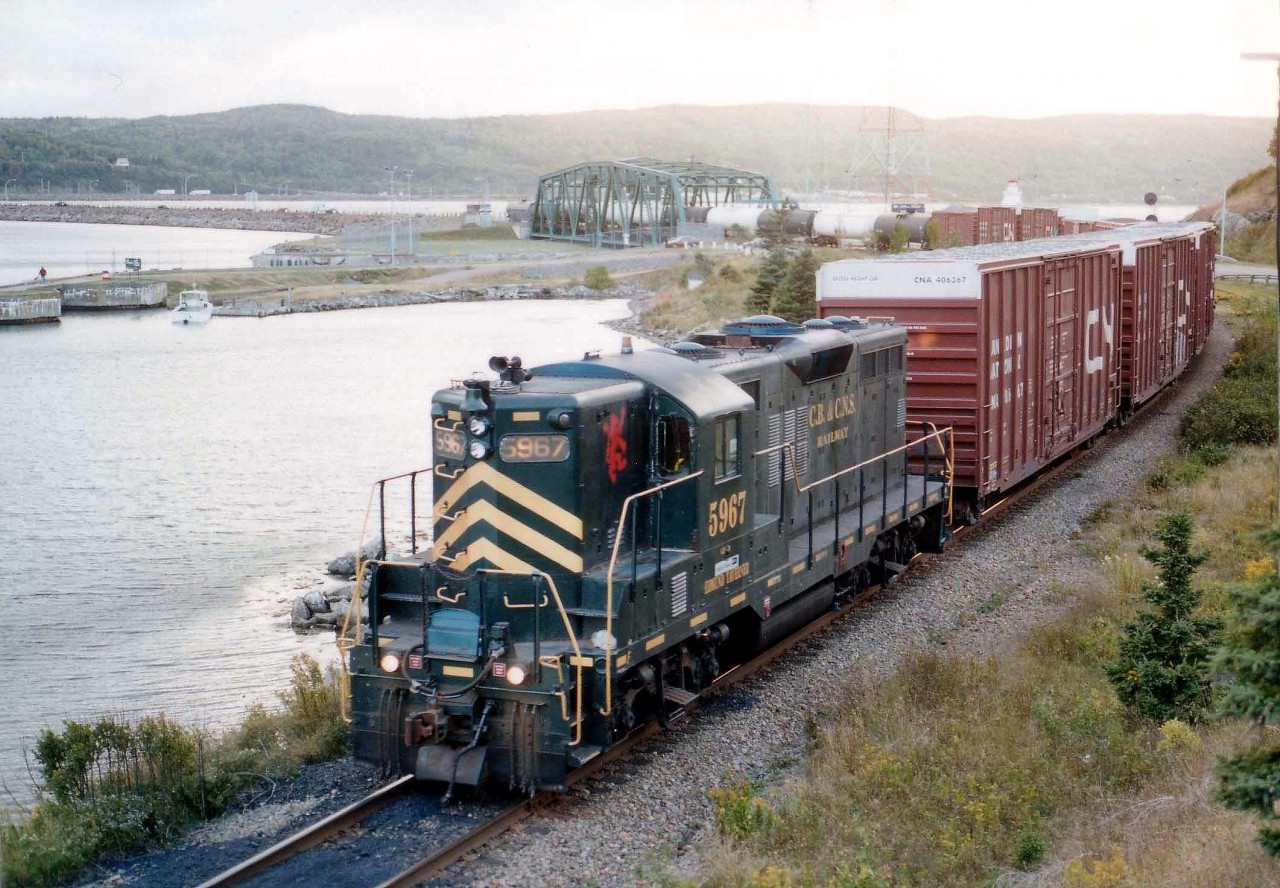 From out of the setting sun comes Cape Breton and Central Nova Scotia GP9 5967 with the local train returning to Port Hawkesbury. The train is seen crossing over the Strait of Canso onto Cape Breton Island. End of train is rolling over the Canso Canal Swing Span. Image taken from the side of Trans-Canada Hwy 104 in Port Hastings, Cape Breton. The CBNS, x-C&0 5967, is no longer. It was scrapped in 2008.