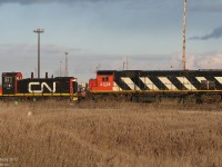 <b><i>Across the field and far away</i></b>. Sitting in the deadline behind the diesel shop, two retired relics of days past linger together on a November evening. CN M636 2338 once hauled heavy transcontinental freights with its 3600 horsepower engine roaring in notch 8. Retired in the late 1990's, she survived the scrapper as the backup Y2K power unit for the shops and has been here ever since, awaiting possible preservation or possible scrapping. SW1200RSm 7316, built in the 1950's for local and roadswitcher service, was upgraded and rebuilt by CN in the 80's, but eventually succumbed to a seized crankshaft that was then cut out. As of late she's been a parts unit for the nearby steel transfer facility's switcher RT-110.<br><br>  Fast forward a few years: 2338 survived on long enough to be purchased by the WNY&P and transported to the US as RPRX 2338, although CN held her up from moving suspiciously long enough for someone to get a photo with the "new" CN 2338 (GE ES44DC) posed side-by-side (methinks there was a railfan in the diesel shop that held it up until then...). 7316 was sold to LDS in Sarnia, where their capable shop will evaluate her for possible rebuild and resale. <br><br> Both have eluded the scrapper's torch, for now.