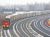 Snow flurries suddenly arrive as CN 570 with a large load of over 50 racks slowly approaches Oshawa and snarls traffic on South Blair.