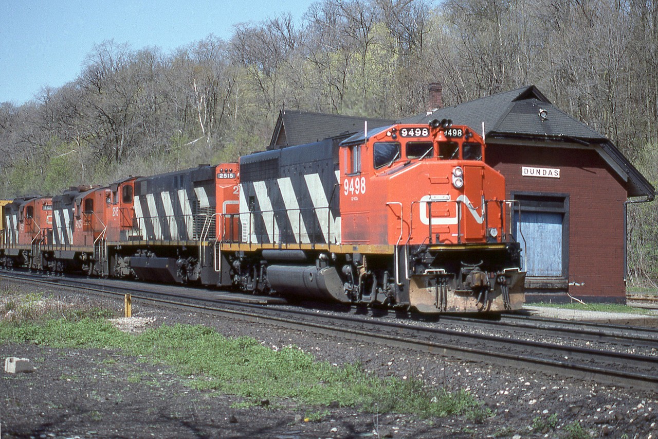 CN GP40-2L(W) 9498 is shown eastbound past the long abandoned Dundas train station in the company of M-420 2515, and GP9’s 4505/4581. Note the ‘extra’ flags on 9498. Sadly, a few months after this photo was taken the ‘Insulbrick’ clad station was torched by vandals and severely damaged. Despite follow up local preservation efforts the station was razed by intentional fire in January of 1988.