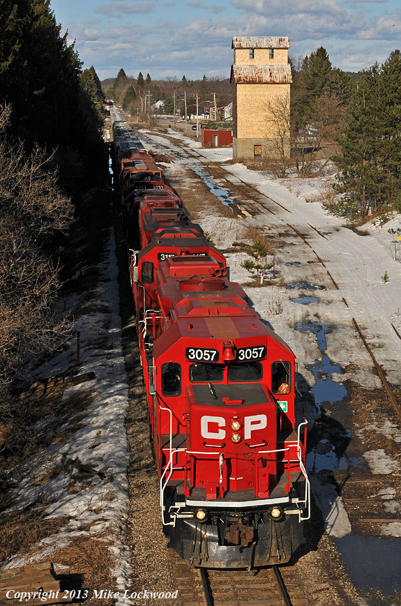 As winter melts away, the siding at Pontypool once again sees daylight, but shall likely remain as disused in the warm weather as it has all winter. At least the mainline still sees a few trains a week, evidenced by the passing of T07 under the watchful eye of the partially restored grain elevator, the new cedar shingles on the west wall gleaming in the low afternoon sun. CP 3057, 3117, 3114, and 8233 lead the way. 1714hrs.