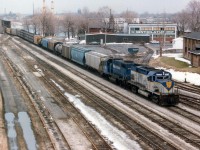 To those of us who wander thru the remnants at Fort Erie CN yard in search of what used to be, this scene is a bit hard to swallow. Look at all the trackage!!!  In this view, D&H 417 and B&M 208 are seen bringing over the daily transfer from Buffalo. One can see the old CN Crew Hostel in the background at right, as well as a couple of stubs behind what used to be a station site; on this track there sometimes were freight cars marked "BOEING" which were left for an aeroplane parts company located up the street. Photo from the Central Avenue bridge now not doable on account numerous thick hydro lines marring the view.