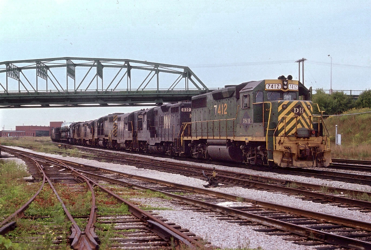 A rail strike in the US in 1978 I believe is the reason for this massive train's presense at Fort Erie. It had run over the CASO from Detroit. D&H 7412 (x-RDG), N&W 830, 2493, D&H 7420, N&W 2709, xxxx and 1572 was the power up front. (Approval for 6 axle units along the line not given until November of 1998) Train is stopped under the Central Av bridge, awaiting clearance to enter the USA via the International Bridge.
