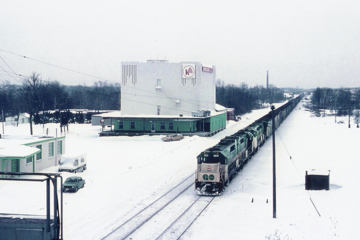 Hard to believe how this once-favourite rail photographers location has changed. Todays generation of trackside buffs would be hard pressed to know where this image was taken. Back in the mid-70s it was not only CP that leased GO power on weekends. The CN did it as well. Here we see a 4 unit GO freight at Aldershot stopped on signal. The signal tower in lower left is gone, the area is now expanded with Aldershot yard trackage and yard lead, the smokestack for Burlington Brick is gone, and so is the fabled Aldershot Cold Storage building, at this time advertising "Kirkelder Spray Misters" on the upper walls (in red). Sidings left and right of the mains are under snow. Power is GO 9801, 9804, 710 and 709. The 9801/9804 became GO 501/504 in 1975, the 710/709 became CN 9677/9676 in 1991.