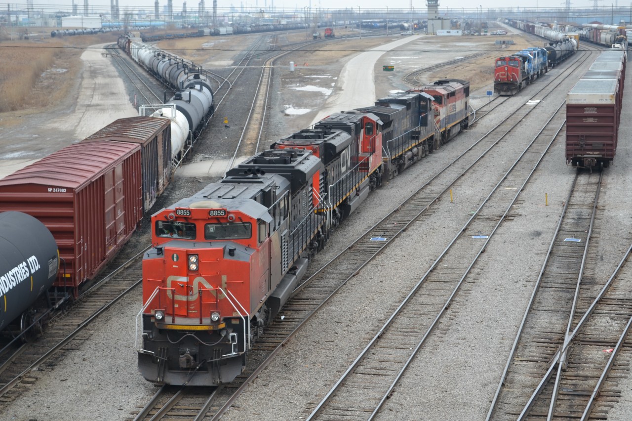 The Power from CN X348, backs to a Stub track, next to the Departure & Arrival yards in Sarnia. The train on the left is CN 330 getting ready to Depart, CN X348 power backing in with CN 8855 - CN 8805 - BCOL 4650 - BCOL 4604, the next track is the power getting ready for train X396 later in the day with CN 2551 - CN 5445 - CN 5484 with the carmen putting up the blue flag to get the train ready for departure. You can see on the right tracks full of cars, from trains that have just came in. In the distance you can see the CSX power sitting waiting to do work, CN locals on different tracks as well working. it was a busy time of day.