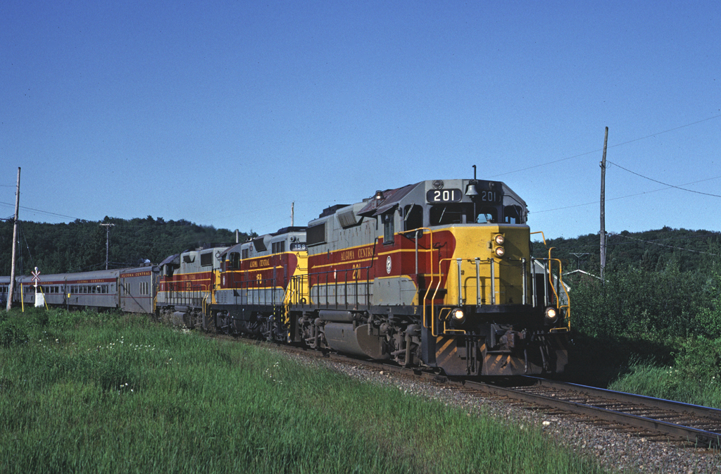 GP38-2 201 leads a GP7 and a second GP38-2 north with train #3 bound for Hearst. They have just crossed the highway at Heyden.