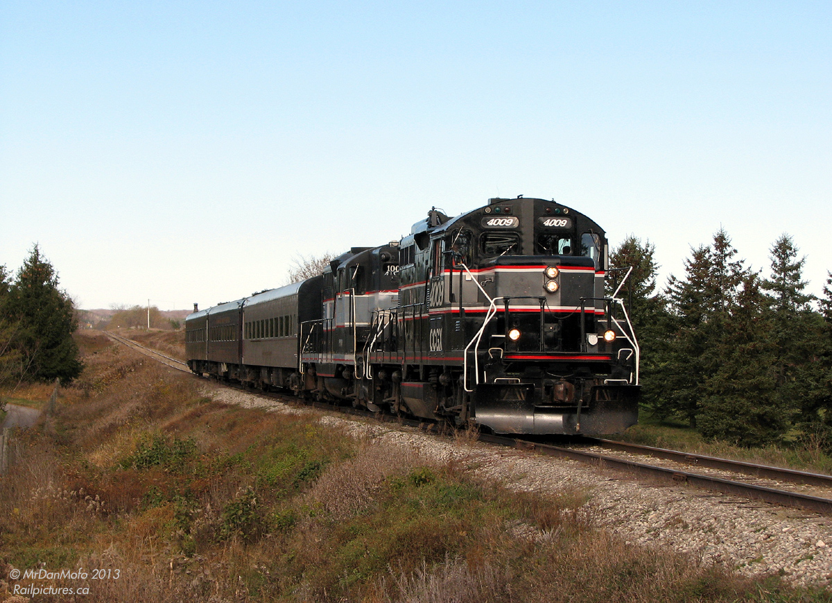 Cruising southbound from Orangeville with three loaded passenger cars and a pair of General Motors GP9's, the Credit Valley Explorer's "Fairwell to 1000" special rare-mileage run heads south through Alton, Ontario in the fall morning light. The up and down track profile here reflects the surrounding rolling hills of the Osprey Valley Golf Course quite well, but we're not here to play a game of golf today.