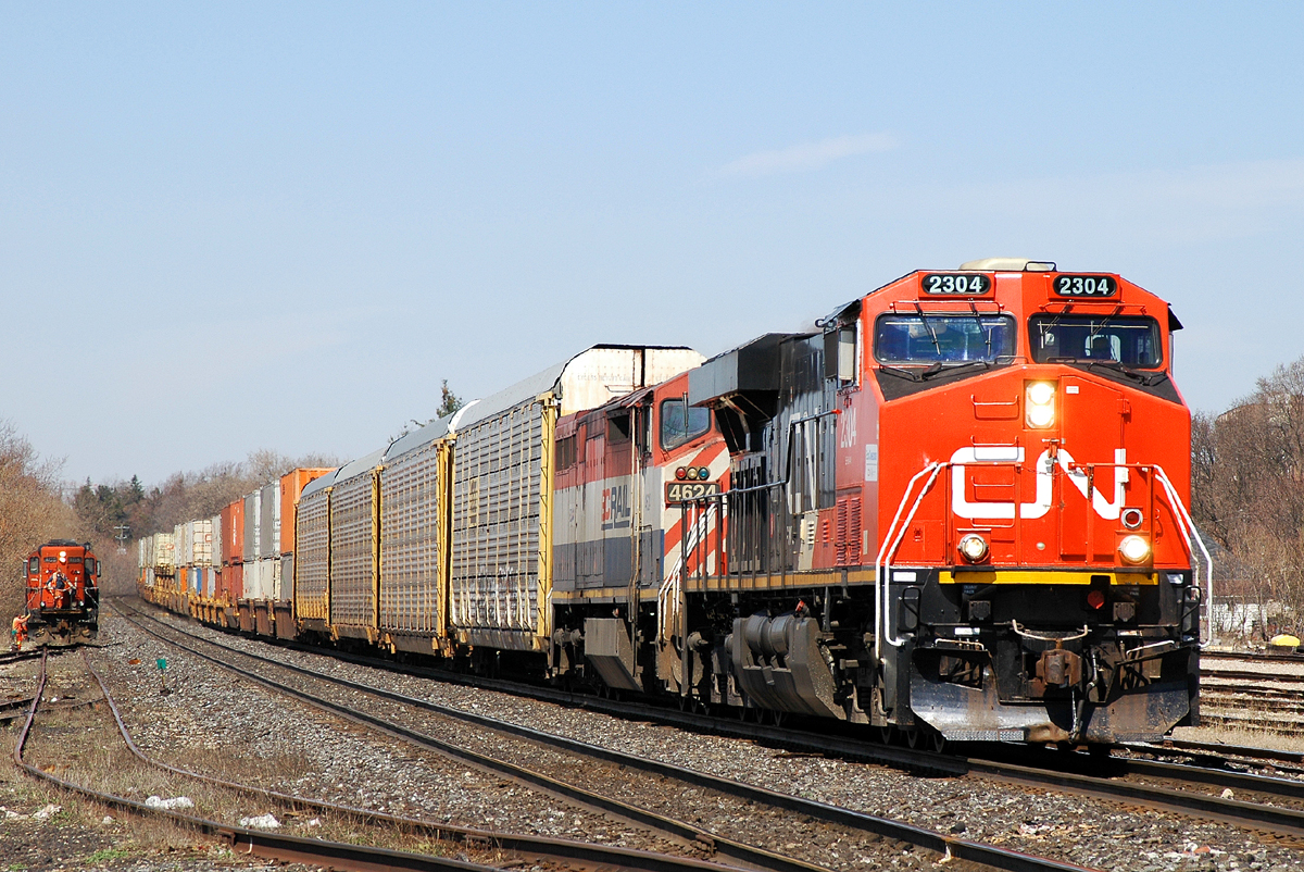 148 rolls downgrade past Brantford with CN 2304 - BCOL 4624, as 580 can be seen emerging from the south yard after spotting a depressed center flat car for unloading