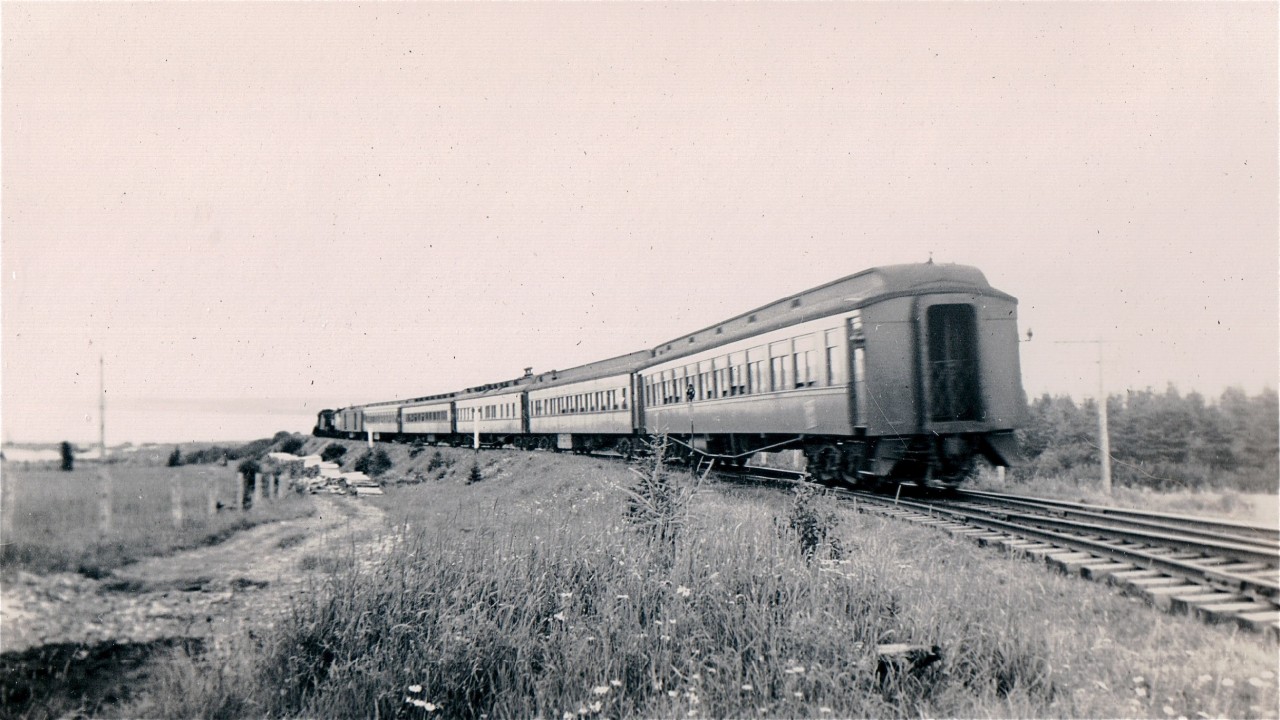 CN Sunday Only Train 71 is near Douglastown en route from Gaspe to Matapedia and Campbellton.  At the head end is a ten-wheeler, probably in the 1130 or 1140 series.  Bringing up the rear is an ex-Canadian Northern Cafe Parlor car, either Mistaya or Tawatinaw.   On weekdays and Saturdays trains 35 and 36 took up to two hours more than 71 (and 72) for the 215 mile trip because of extra stops and considerably more head-end traffic.