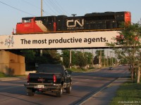 <b><i>GM over GM</i></b><br><br>Rumbling over traffic (including a GMC pickup truck) on the busy Islington Avenue below, CN #115 with 8851 on point heads east after departing Brampton Intermodal Terminal and crossing the massive Humber River bridge (Mile 4.3 of the Halton Sub). Skirting the north side of Toronto just north of Steeles Ave, a stone's throw away one can note CP's MacTier Subdivision crossing just north of the Emery industrial area.<br><br>Built by Electro Motive's General Motors Diesel Division in London ON, SD70M-2 8851 was as good as it got in terms of new power on CN at the time. Alas, with the Caterpillar takeover and elimination of the London plant they're no longer made with Canadian pride, instead in work-to-rule Muncie, Indiana at lower wages. A sign of the times.