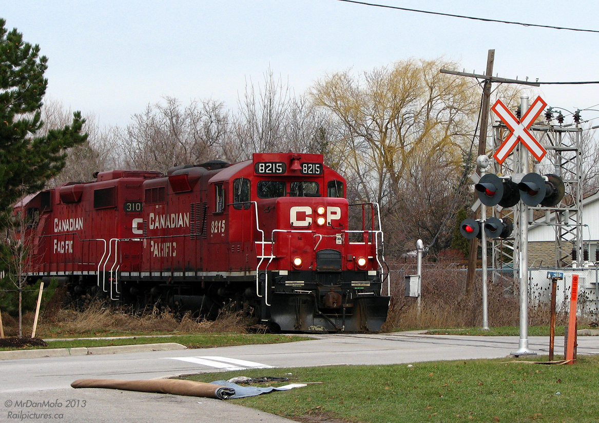Red Interlopers!Heading south on the OBRY's Owen Sound Spur, the CP Streetsville Turn with 8215 & 3105 crosses Alpha Mills Road on the way back to Streetsville Junction as light power. After having switched a customer up the line (likely Kaotin Natie north of Highway 401), the pair of Geeps are heading back to the Galt Sub mainline to begin switching PDI's transloading facility inside the old wye area.Today's rare catch began with driving over the crossing at Mississauga Road on the way home, and catching a glimpse of a headlight in the distance. Assuming it was the OBRY, a quick detour to Alpha Mills revealed the photographer was mistaken, but yielded a far greater prize. While shortline owner Orangeville Brampton Railway handles operations and switching on most of the line, CP retains service on the portion south of Mile 2.4, of which there are one or two customers remaining that get CP-switched every so often.And the carpet? Your guess is as good as mine...