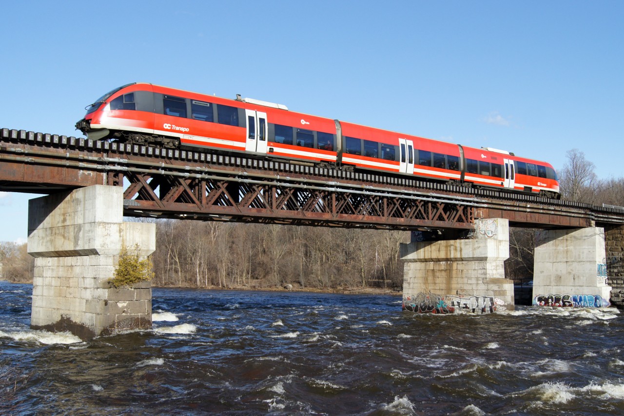 In the final week before a 16 week shutdown to prepare for the arrival of new trains and a doubling in service levels, OC Transpo (Capital Railway) C3 crosses the raging Rideau River after departing Carleton Station at Carleton University.