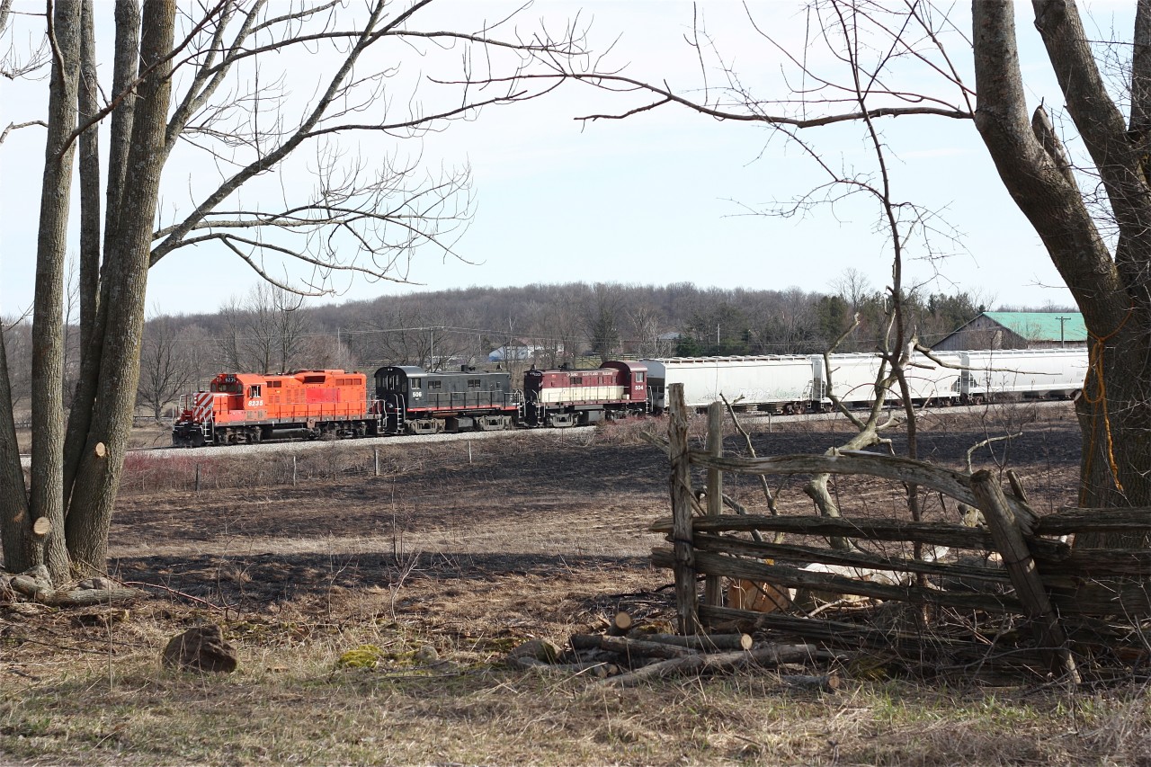 The days OSR southbound train is returning back to Guelph Jct. from Guelph as it passes south of Corwhin. The area was ravaged by an ice storm the previous week, which downed a number of trees, while in the field the scares remain from a large grass fire set a few days earlier.