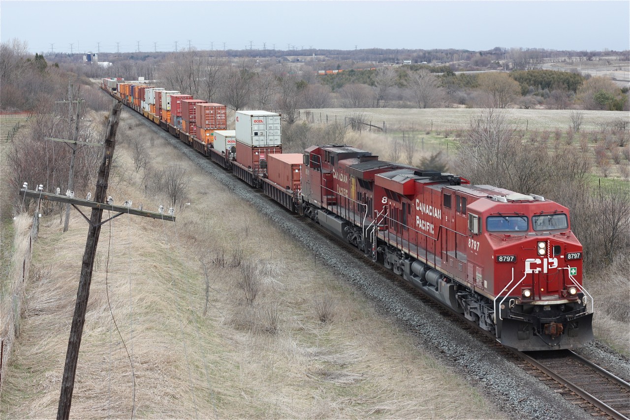 A pair of CP GE's are in charge with their train stretched across the rolling countryside at Newtonville.
