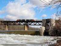After several days of rain and spring runoff, the water level on the Grand River is quite high as C.N. 8949 leads a westbound freight over the trestle at Paris, Ont.
