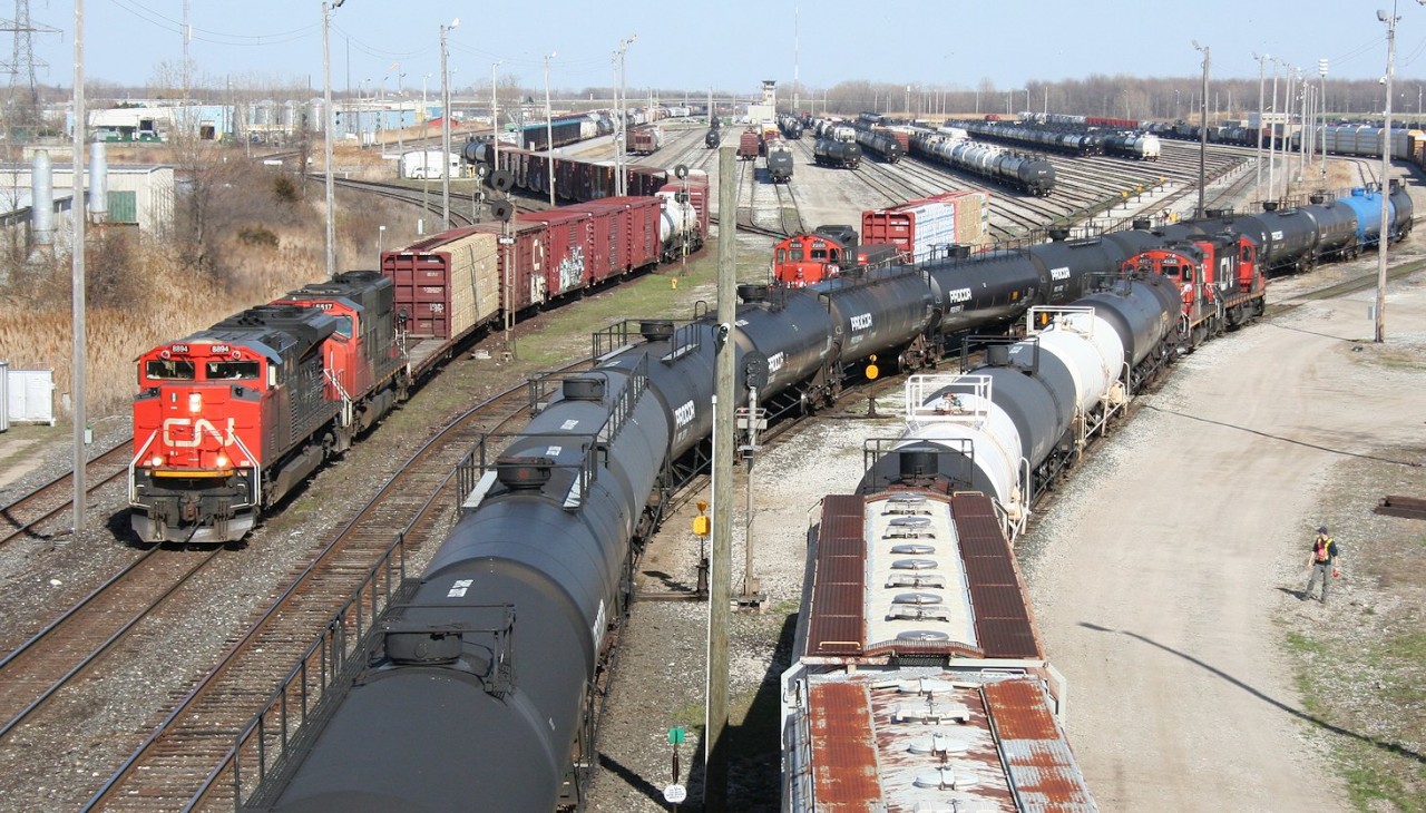 CN train no. 501 (CN 8894 West, at left) departs Sarnia Yard for Port Huron, MI while alongside in the yard there is a flurry of activity as train 331 (middle, power not in shot) has just arrived and is in the process of yarding its train while a yard job works local cars in the secondary "C" yard behind the photographer. Meanwhile another yard job waits for 331 to clear up so it can continue the process of classifying cars in the main yard.