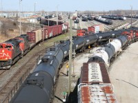 CN train no. 501 (CN 8894 West, at left) departs Sarnia Yard for Port Huron, MI while alongside in the yard there is a flurry of activity as train 331 (middle, power not in shot) has just arrived and is in the process of yarding its train while a yard job works local cars in the secondary "C" yard behind the photographer. Meanwhile another yard job waits for 331 to clear up so it can continue the process of classifying cars in the main yard.