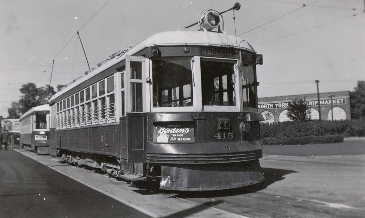 TTC 415 awaits its next run, parked on one of the two tracks which formed the North Yonge side of the Glen Echo terminal.  The North York Township Market in the background is housed in what had been the Toronto & York Radial Railway car house opened in 1922 when the southern terminus of the "Radial" was cut back to the city limits at the same time as regular street car service on Yonge Street within the city was extended north to the same spot.  The entire site is now occupied by a Loblaws supermarket and a two-level parking garage.