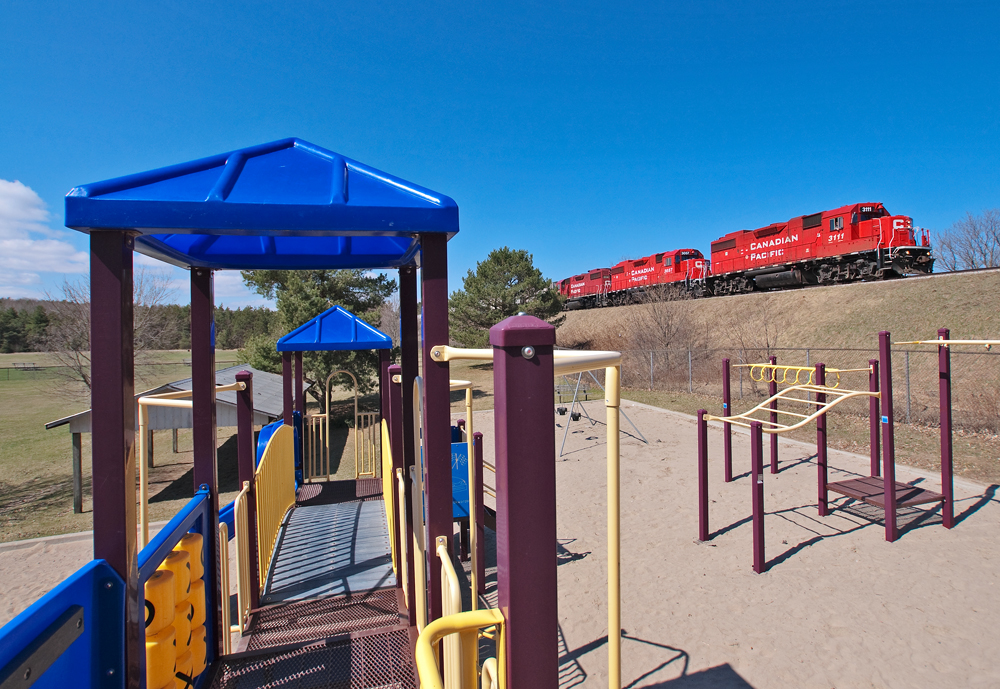 The quiet solitude all around the playground in the town of Burketon is broken by the sound of GP38-2's hauling train T08 east at a slow pace.