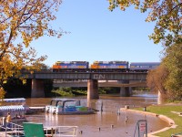 VIA's westbound "Canadian" pulls out across the Assiniboine River at "The Forks" in downtown Winnipeg. Fall is already in the air with the trees along the river already turning yellow.