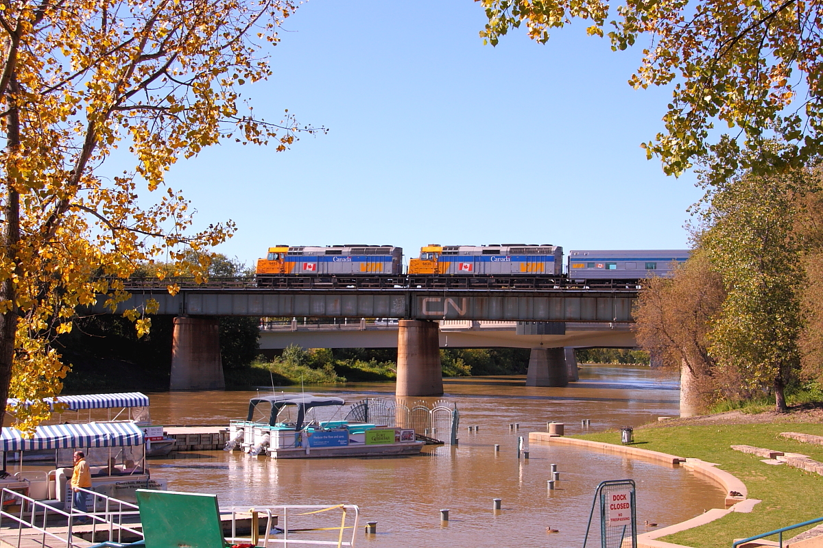 VIA's westbound "Canadian" pulls out across the Assiniboine River at "The Forks" in downtown Winnipeg. Fall is already in the air with the trees along the river already turning yellow.