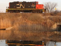 After working the nearby Ford plant and spotting some autoracks for loading, CN GP9RM 7007 heads back light to Oakville Yard, its reflection cast in the still waters of a nearby pond. The moon is in the sky, the last light of the day is slowly fading to darkness.