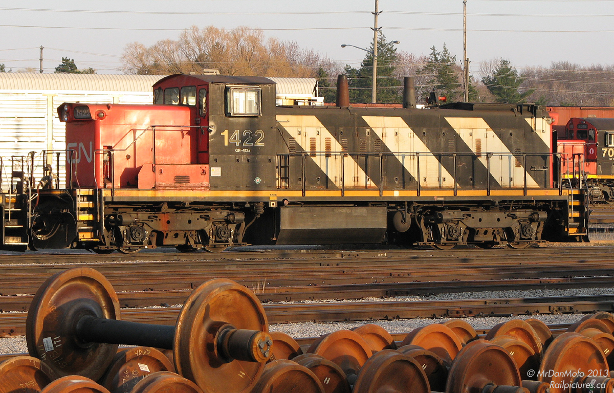 Weekend Warrior.Sitting amid GP9RM's of similar vintage and new wheelsets piled up nearby, CN GMD1 1422 isn't out partying this Friday evening. Rather, she's slumbering in Oakville yard as the sun sets on a busy work week, awaiting the call of duty another day.Having long traded her lightweight branchline A-1-A Flexicoil trucks in for a set of B-B's, this former prairie gal and her other GMD-1 siblings now work light road duties and switching across the CN system.